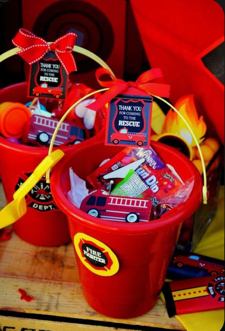 two red buckets filled with candy sitting on top of a wooden table next to other items