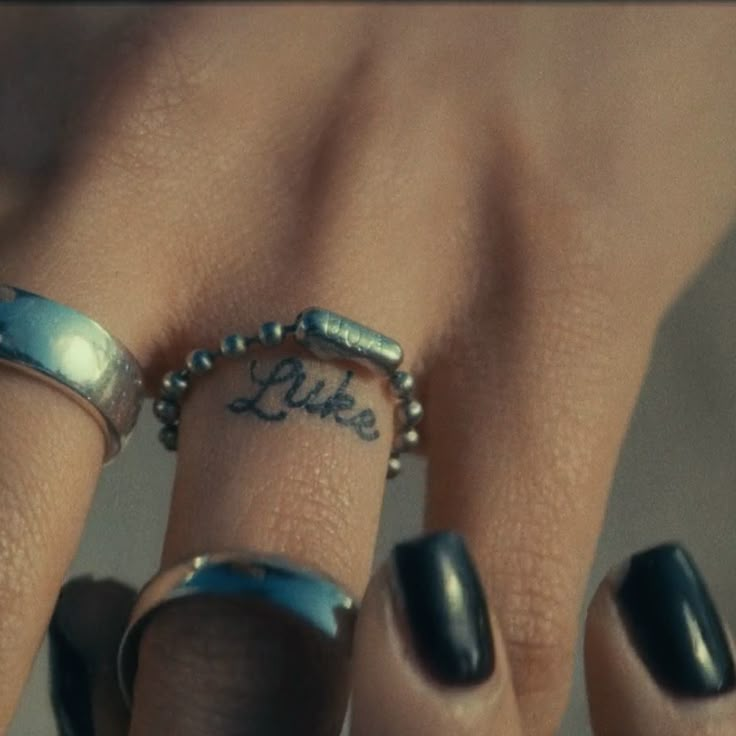 a woman's hand with two rings on it and the word like written on her finger