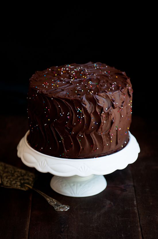 a chocolate cake with sprinkles sitting on top of a white platter