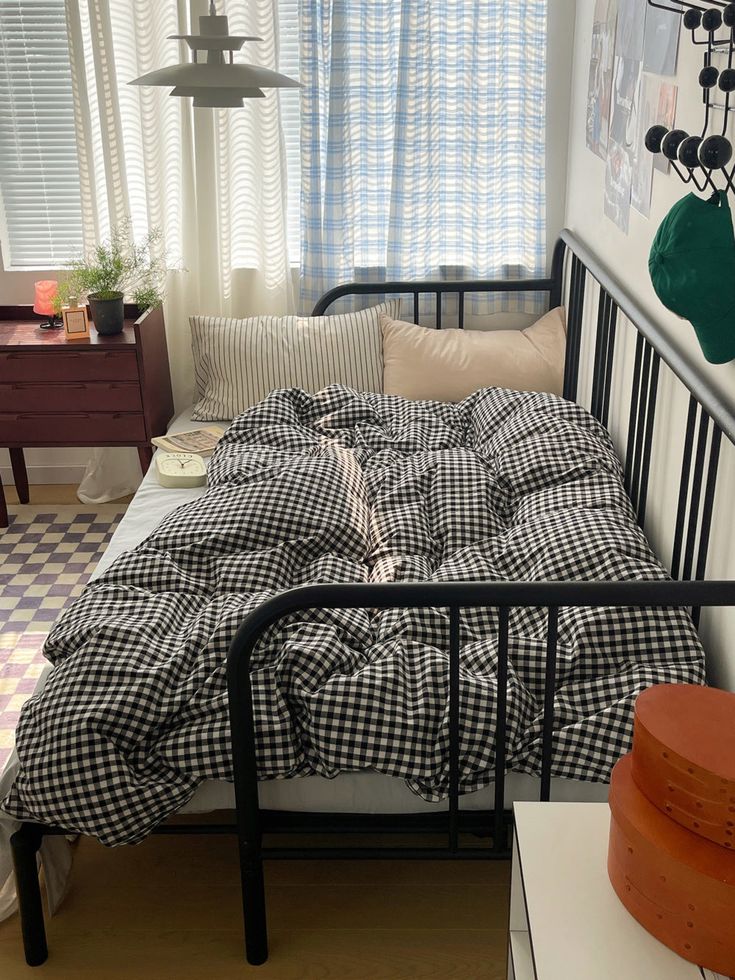 a black and white checkered bedspread in a small room with an iron bed frame