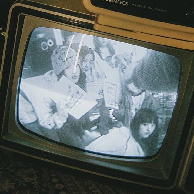 an old television sitting on top of a table next to a tv set with people in it