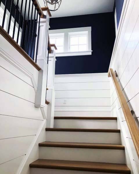 stairs leading up to a window in a blue and white house with wood handrails