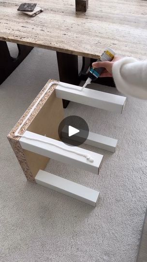 a person is painting the side of a table with white and brown paint on it