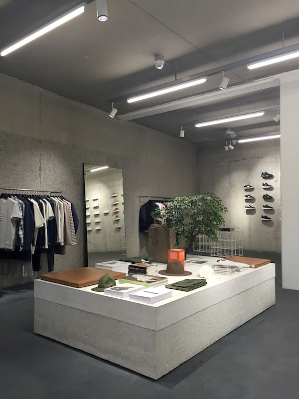 a clothing store with clothes hanging on the wall, and a plant in the middle