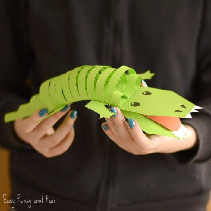 a woman holding a green paper alligator in her hands