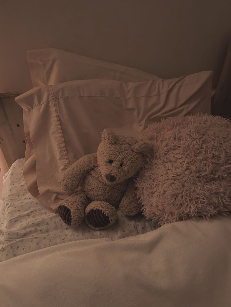 a teddy bear laying on top of a bed