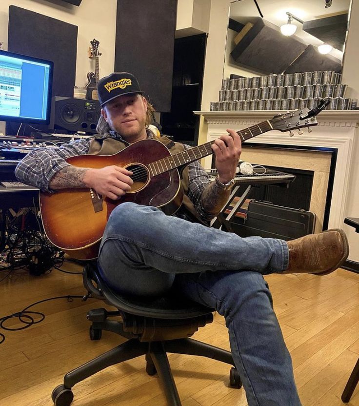 a man sitting in a chair playing an acoustic guitar