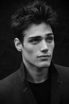 black and white photo of a young man in a suit looking at the camera with an intense look on his face