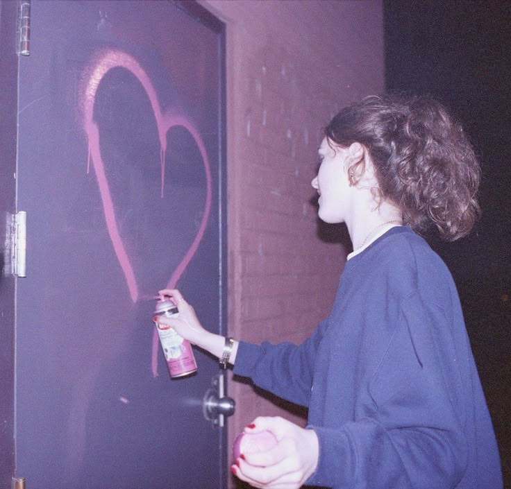 a woman spray painting a heart on a door