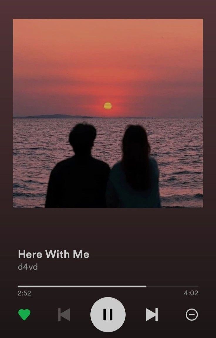 two people are sitting on the beach watching the sunset