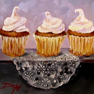 three cupcakes with white frosting on top of a glass plate in front of a purple background