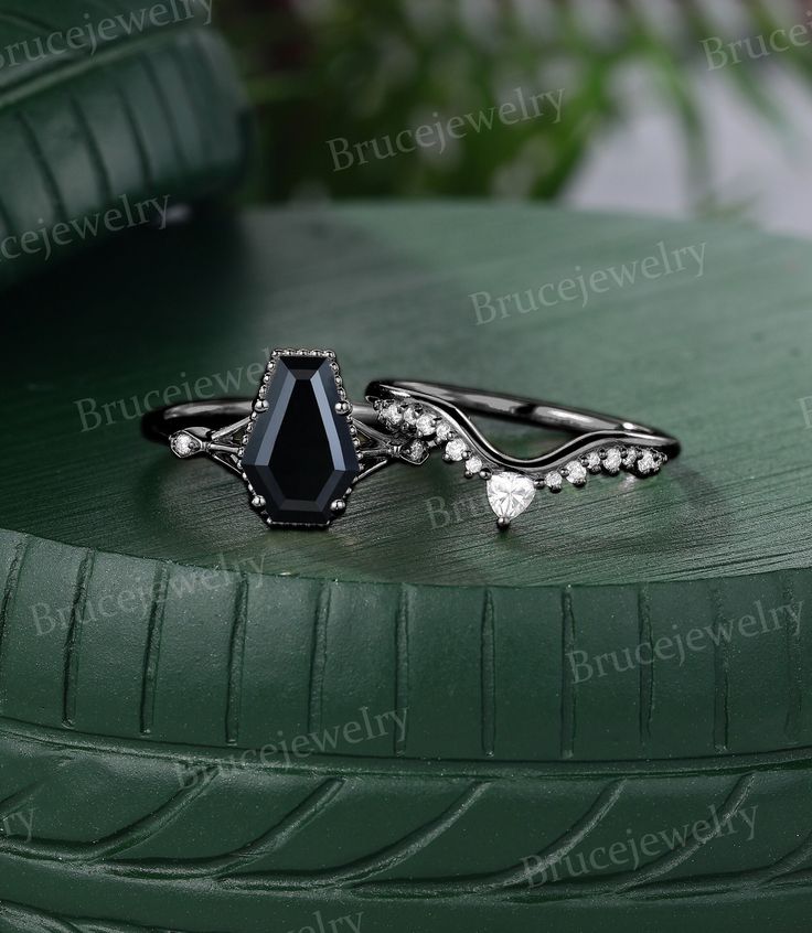 a black diamond ring sitting on top of a green tire treading surface with greenery in the background