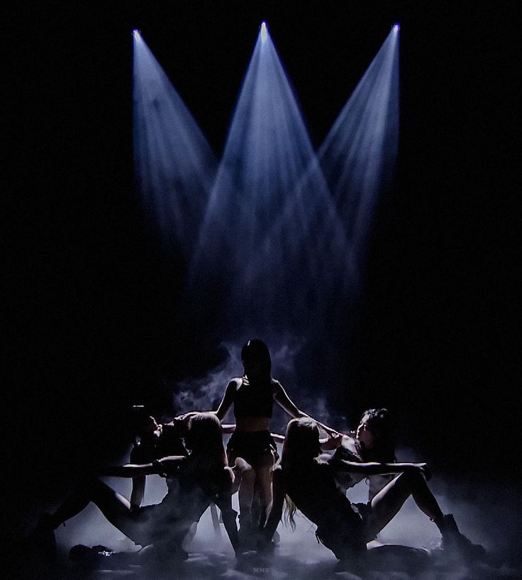 the dancers are performing on stage with their arms around each other in front of spotlights