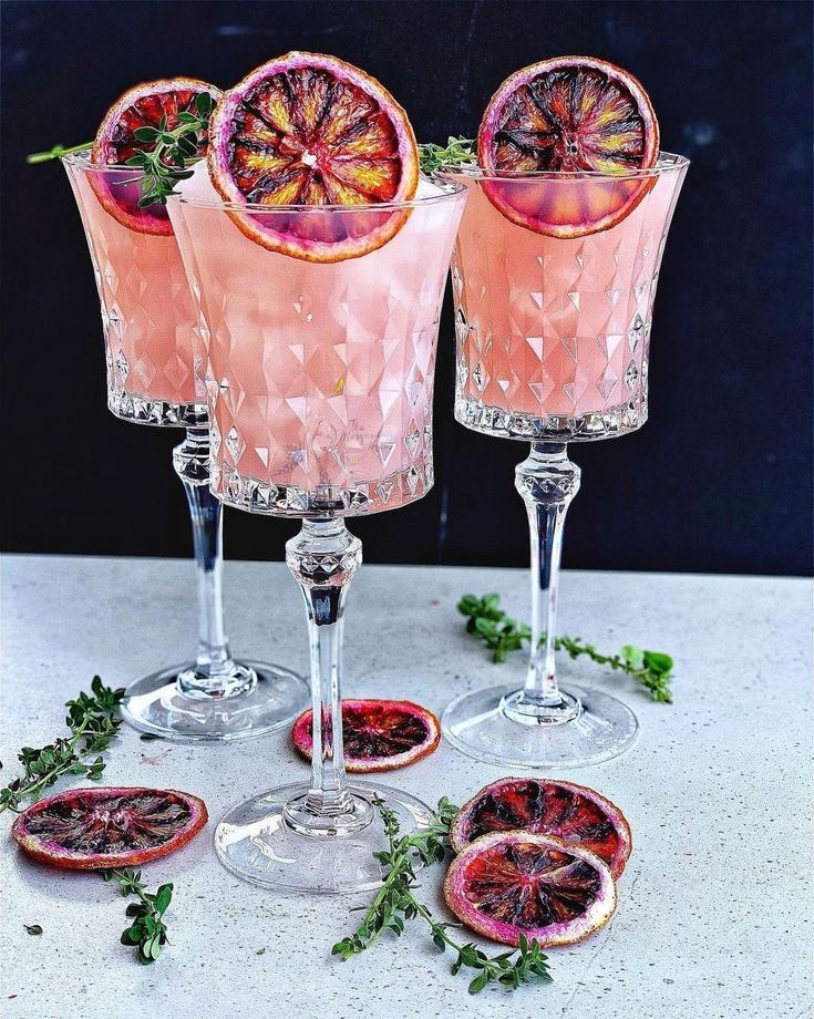 three wine glasses filled with blood oranges and garnish