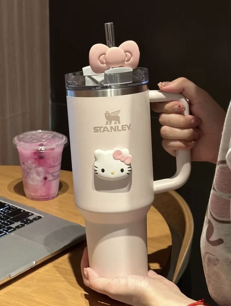 a woman is holding a hello kitty coffee cup