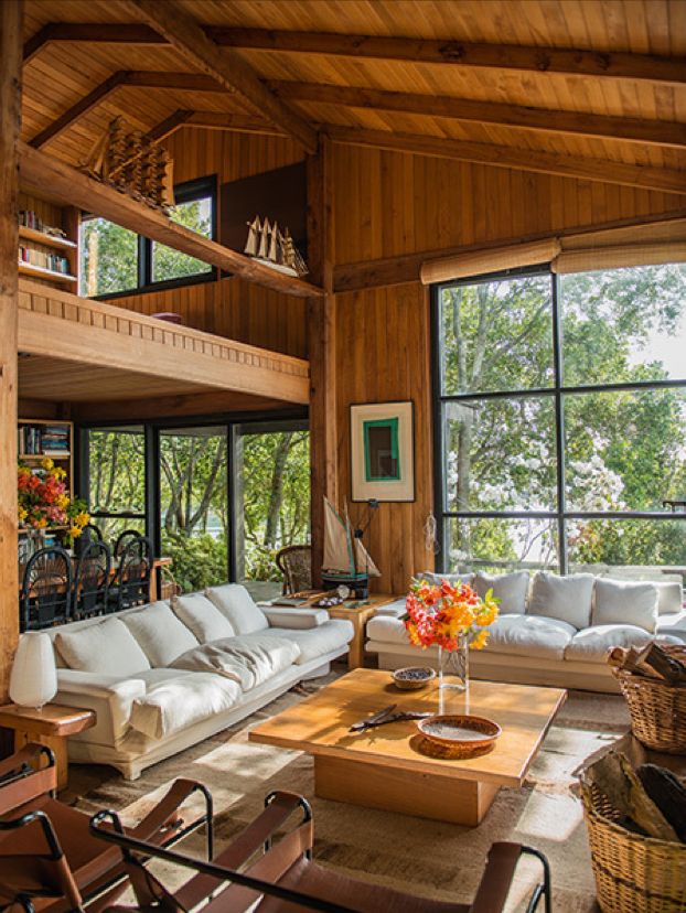 a living room filled with lots of furniture next to large windows on top of a wooden floor