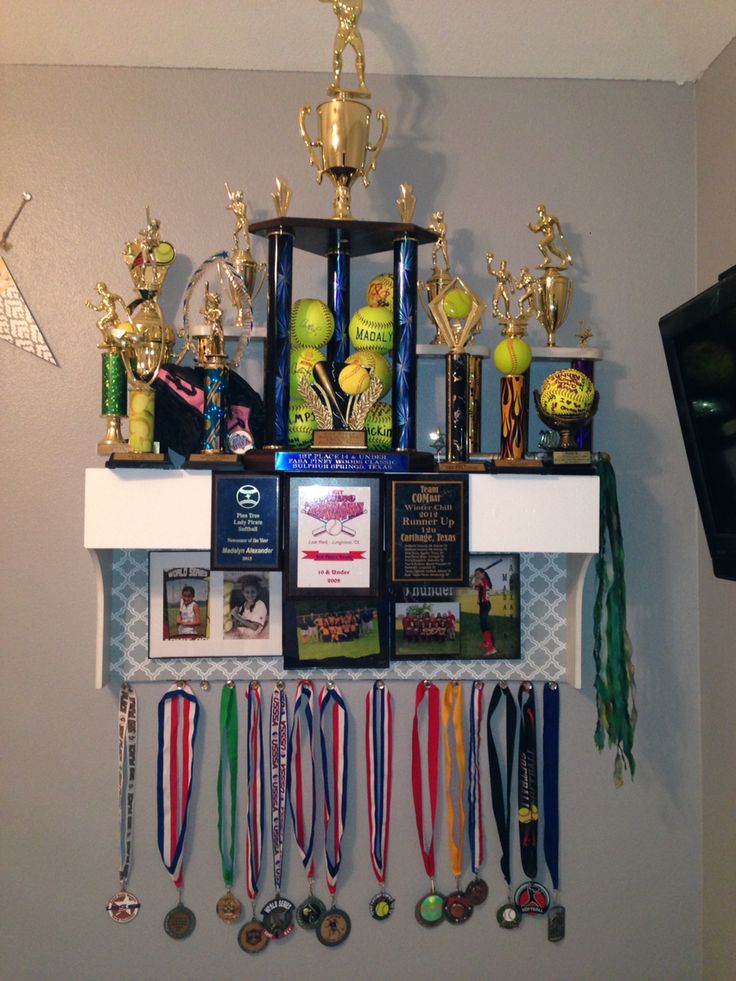 a wall mounted shelf filled with trophies and medals