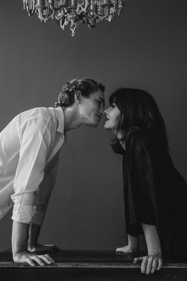 a man and woman kissing in front of a chandelier