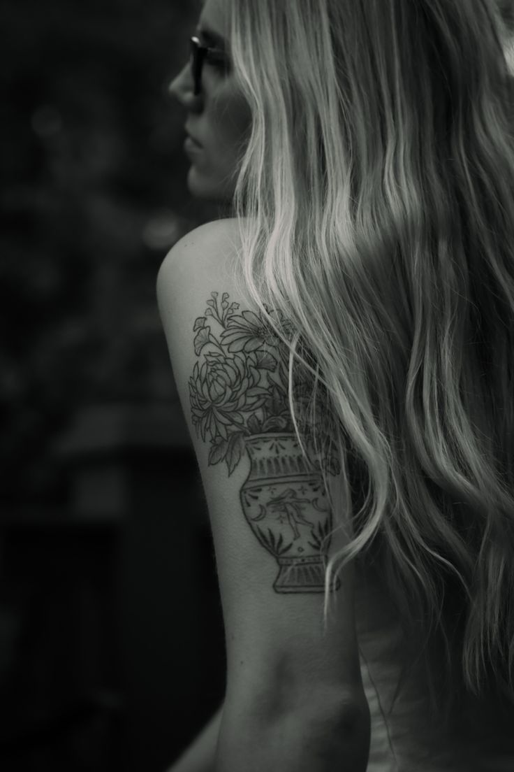 a woman with a flower pot tattoo on her upper arm and lower back half sleeve