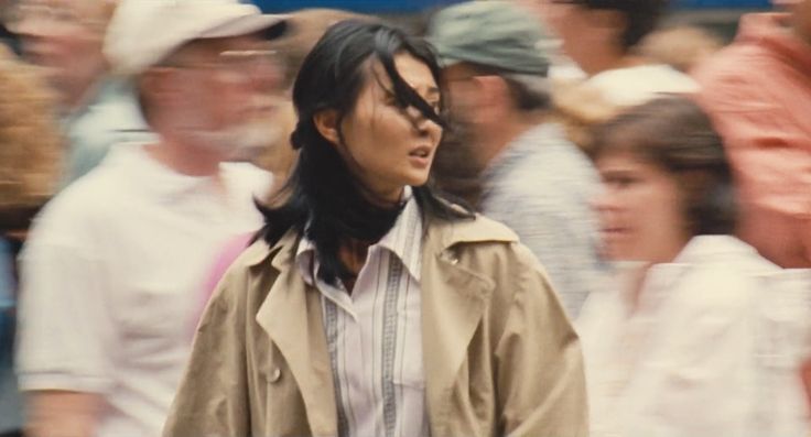 a blurry photo of a woman walking in front of a crowd with people behind her