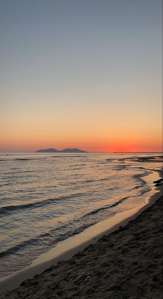 the sun is setting over the water at the beach