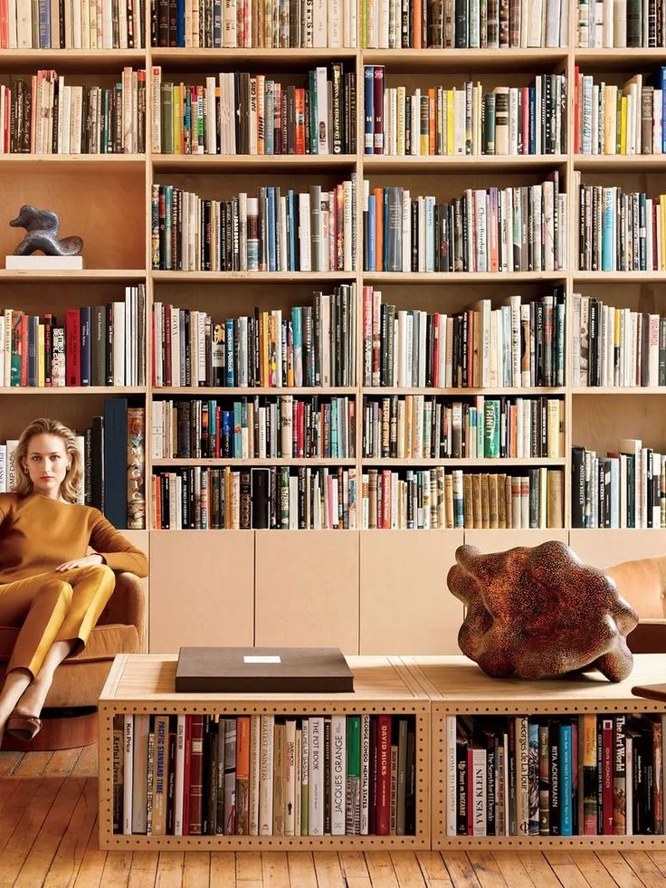 a woman sitting on a couch in front of a bookshelf filled with books