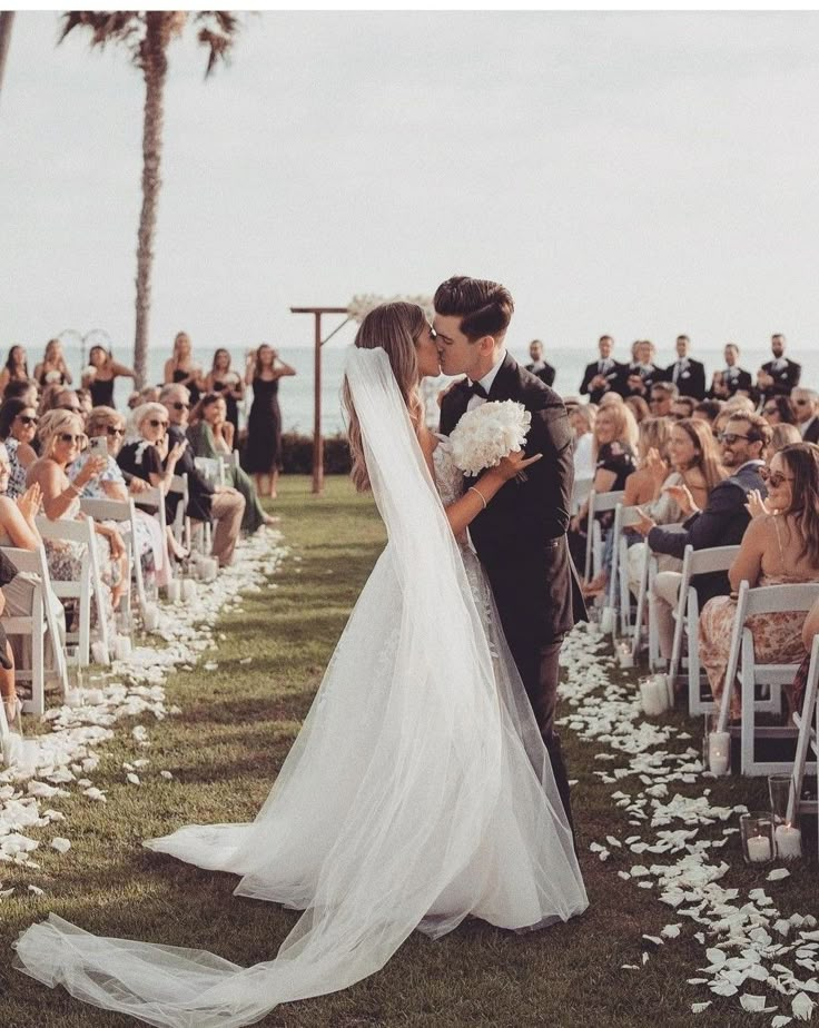 a bride and groom kiss as they walk down the aisle at their outdoor wedding ceremony