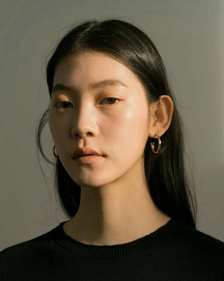 a woman with long black hair wearing gold hoop earrings