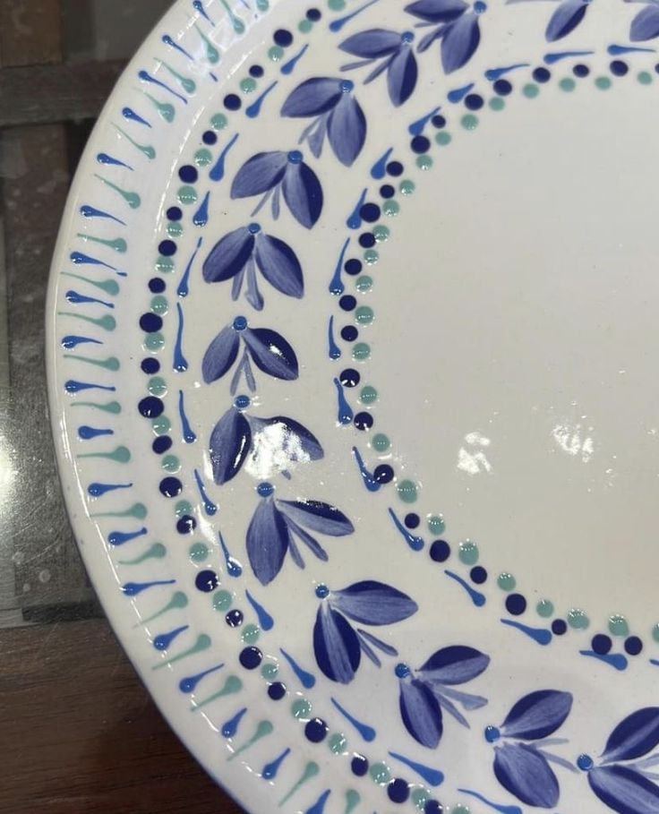 a blue and white plate sitting on top of a wooden table next to a brick wall