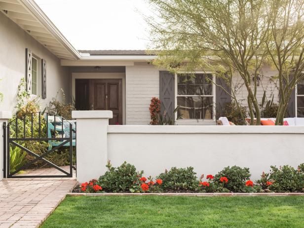 a white house with red flowers in the front yard