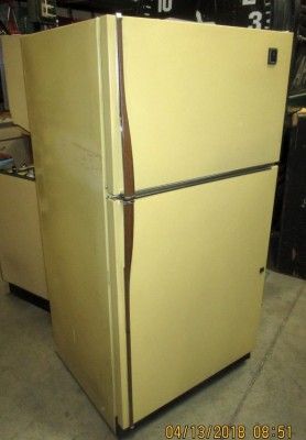 an old yellow refrigerator sitting in a garage