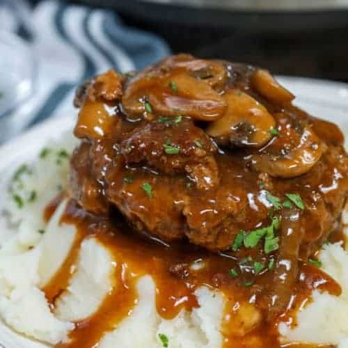 a white plate topped with mashed potatoes covered in gravy and meatballs