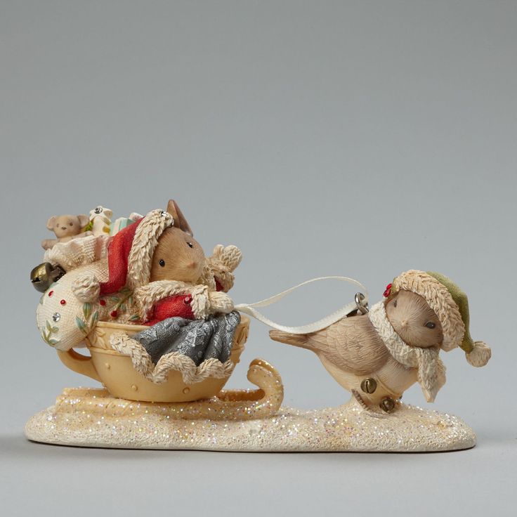 two figurines of mice riding in a sleigh