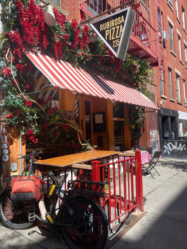 a bike is parked in front of a pizza stand on the sidewalk near a building