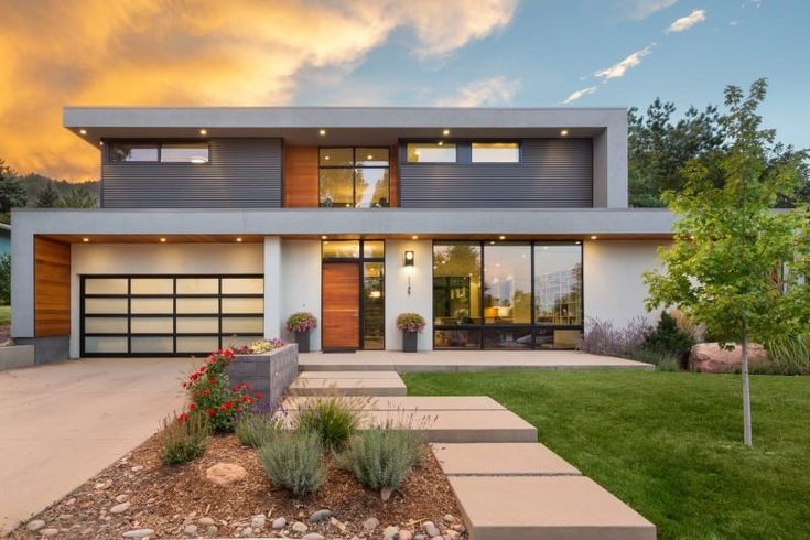 a modern house with large windows and lots of grass in the front yard at sunset