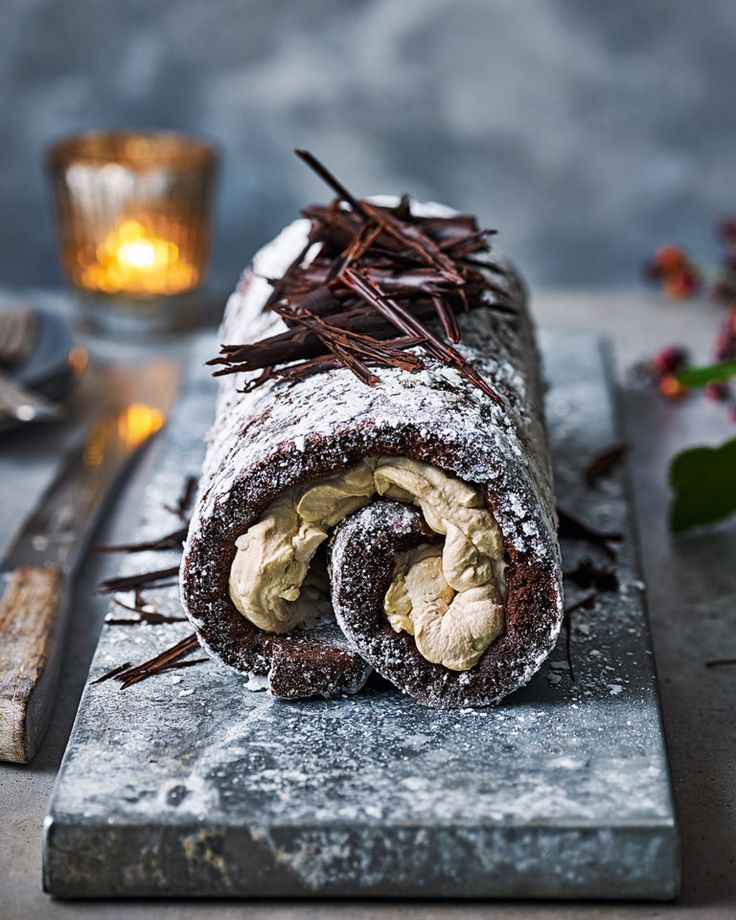 a chocolate roll with powdered sugar and cinnamon on top sitting on a cutting board