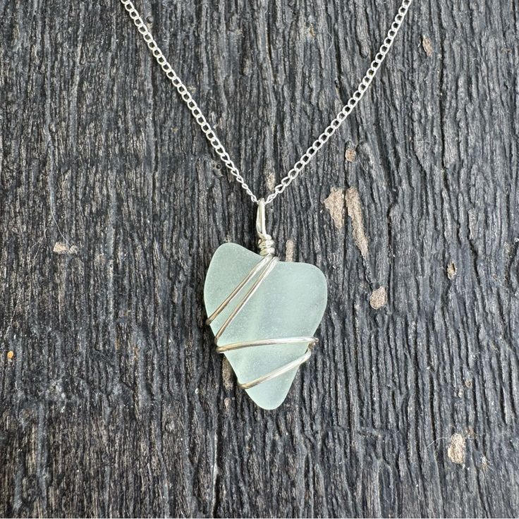 a necklace with a heart shaped glass piece hanging from it's side on a wooden surface