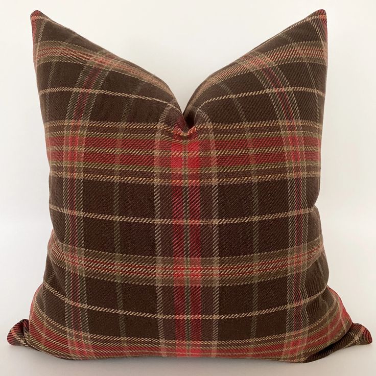 a brown and red plaid pillow on a white background