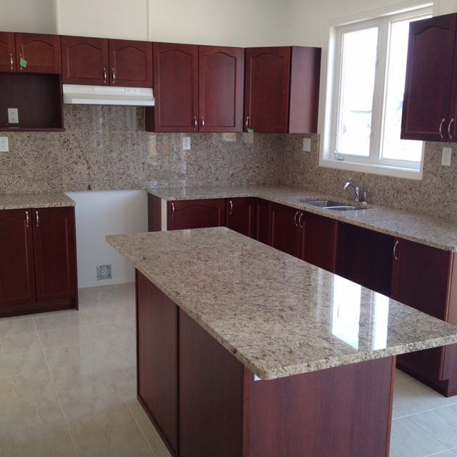 an empty kitchen with granite counter tops and wooden cabinets, along with white tile flooring