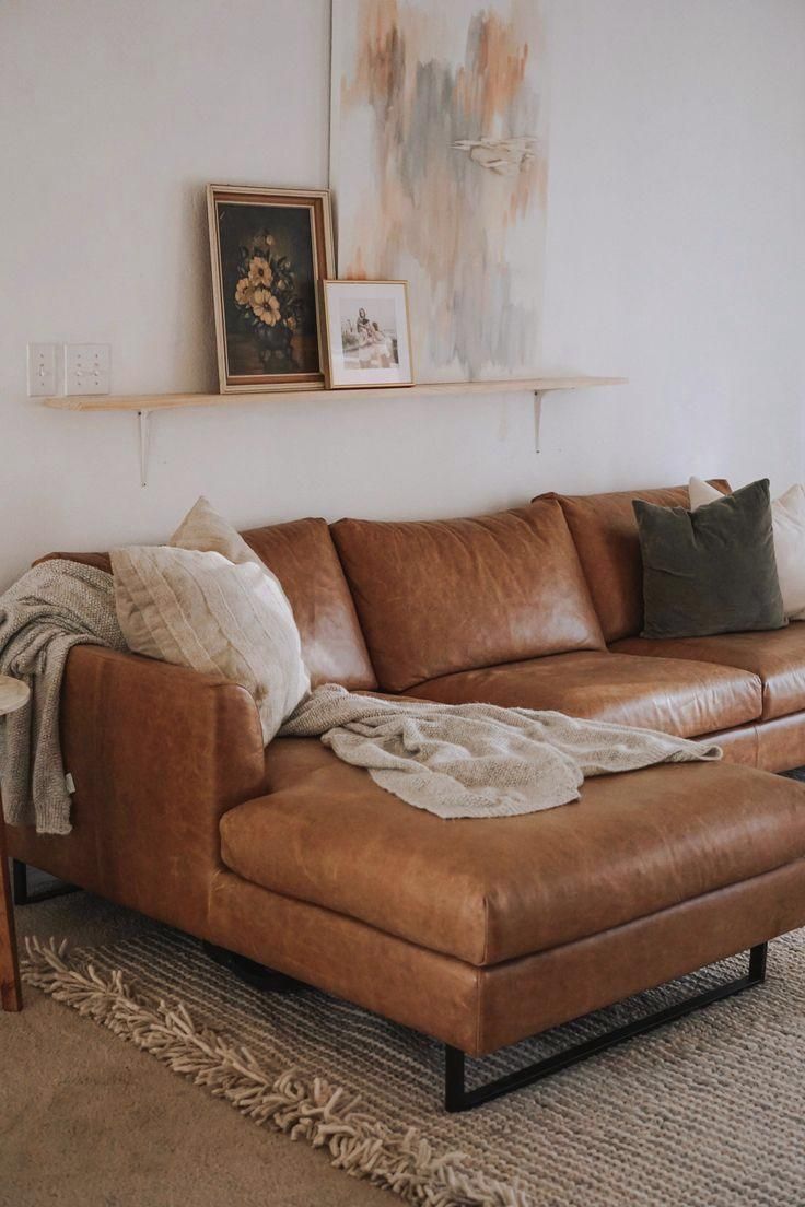 a living room with a couch, ottoman and pictures hanging on the wall above it