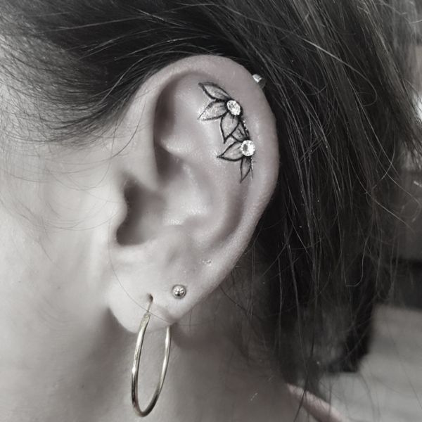 a close up of a person wearing ear piercings with flowers on it's side