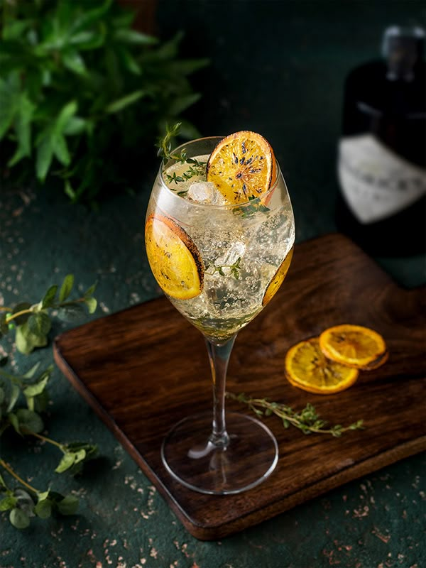 a glass filled with ice and lemons on top of a wooden cutting board