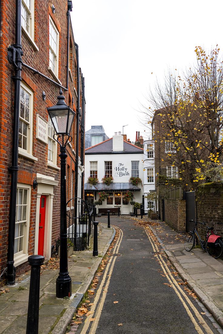 an empty street in the middle of some brick buildings with red doors on each side