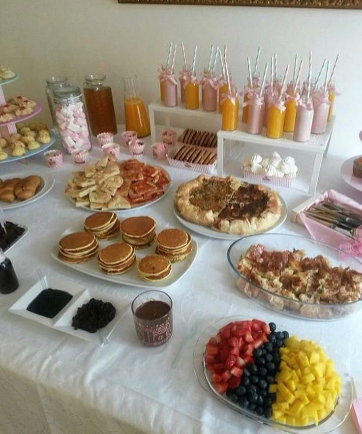 a table topped with lots of desserts and pastries on top of white clothed tables