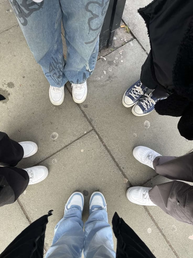 several people standing in a circle with their feet on the ground and one person wearing white shoes