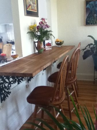 a long wooden table sitting in the middle of a living room next to a plant