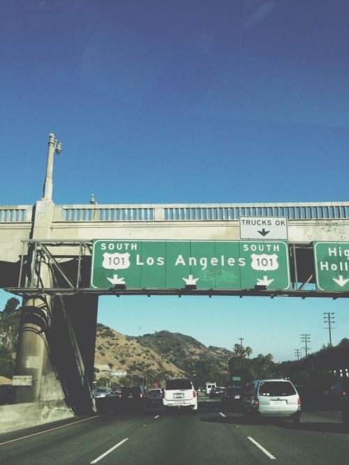 an overpass with several freeway signs and cars driving underneath it on a highway in los angeles, california