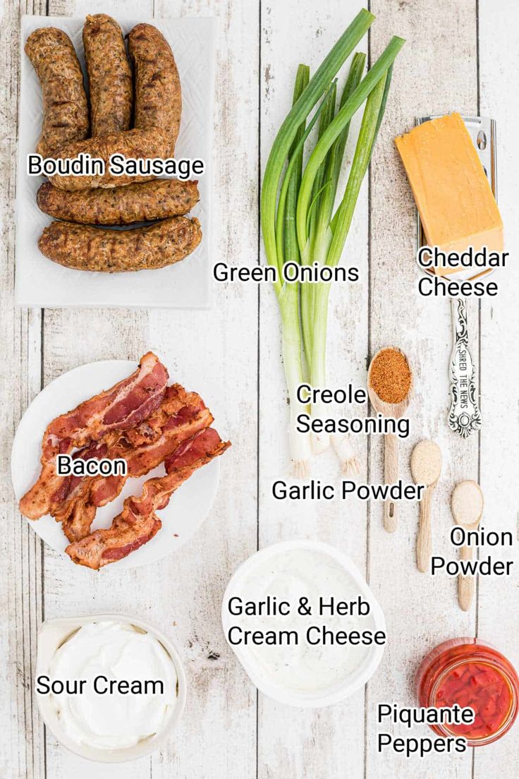 the ingredients to make sausages are laid out on a white wooden table, including onions, green onions, bacon, garlic, sour cream, parmesan cheese and bread