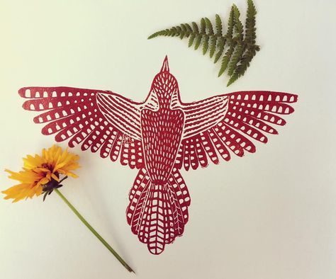 a red paper cut bird next to a yellow flower