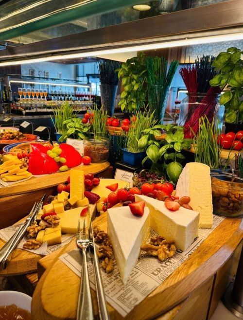 many different types of cheeses and fruits on display in a buffet area at a restaurant